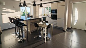 A modern kitchen with a central island, bar stools, and a dining table. - Whole house (Saint-Jean-Lachalm)