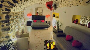 A cozy room with a stone ceiling, a bed with heart-shaped pillows, a sofa with heart-shaped cushions, and a small table with candles and a bottle. - Whole house (Saint-Jean-Lachalm)