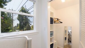 A hallway with a window, white walls, and a wooden floor. There are shelves with storage boxes and a hanging rack. - Cottagecore charm beside the redwoods—steps to trails, minutes to beaches and downtown Arcata. (Arcata)