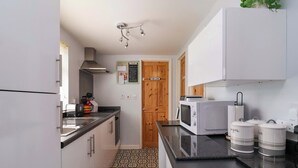 Una cocina compacta equipada con microondas, hervidor y recipientes de almacenamiento.