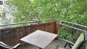 A deck with a table and two chairs, surrounded by a bamboo fence and lush greenery.