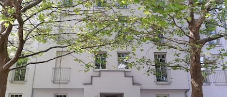 Un immeuble de deux étages, à la façade blanche, portant le numéro 12, et dont la porte est située au centre.