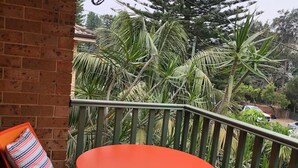 A wooden deck with a round orange table and matching orange chairs, surrounded by a green metal railing.