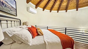 Ein Schlafzimmer mit Bett, Kissen, Decke, Lampe und Klimaanlage.