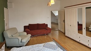 A living room with a sofa, armchair, and a large wardrobe.