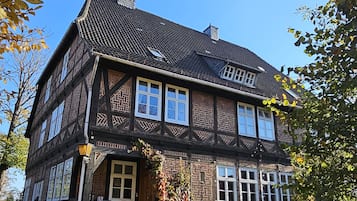Ein traditionelles Fachwerkhäuschen mit einem steilen Satteldach, zahlreichen Fenstern und einer Steintreppe, die zum Eingang führt.