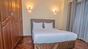 Una habitación de hotel con una cama grande, un armario de madera y dos luces fijadas a la pared.