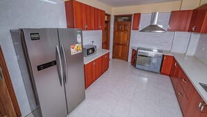 Una cocina con electrodomésticos de acero inoxidable, armarios de madera y piso de baldosas.