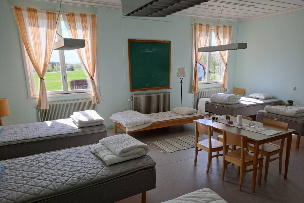 A dormitory room with bunk beds, a study table, and a chalkboard.