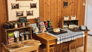 Un interno rustico in legno con un tavolo che espone diversi cibi e condimenti, una lavagna con il menu e una panca di legno.