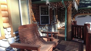 A wooden deck with a bench, stone wall, and a garage door in the background. - Luxury w Spa Foosball - DeCarlo House (Big Bear Lake)