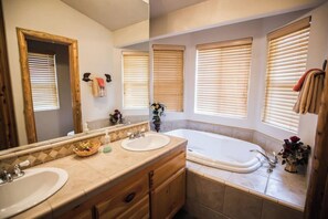 Un bagno con due lavandini, una vasca da bagno e ampie finestre con persiane.