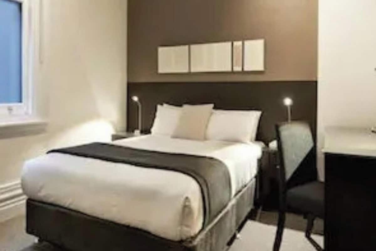 A hotel room with a bed, a desk, and a chair.