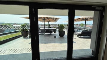 Un patio moderno al aire libre con mobiliario y sombrillas, vista del paisaje urbano y plantas en macetas.
