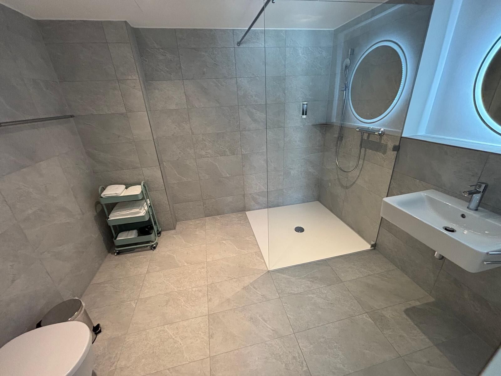 A modern bathroom with a shower, toilet, and sink.