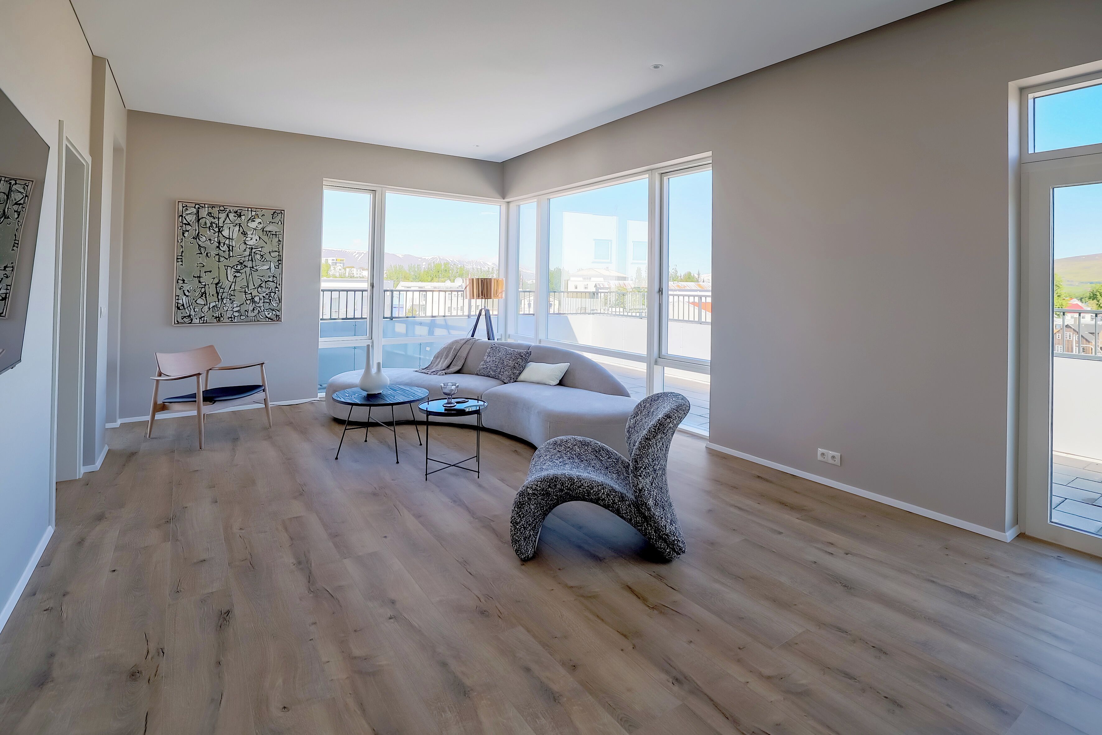 A spacious living room with a large window, a sofa, a coffee table, and a unique chair.