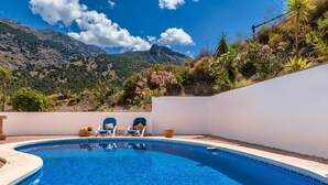 Una piscina con dos sillas de descanso y una pared blanca.