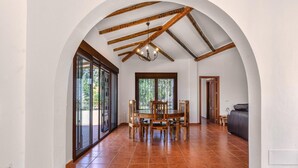 Un comedor amplio con una mesa y sillas de madera, ventanas grandes y un techo alto con vigas a la vista.