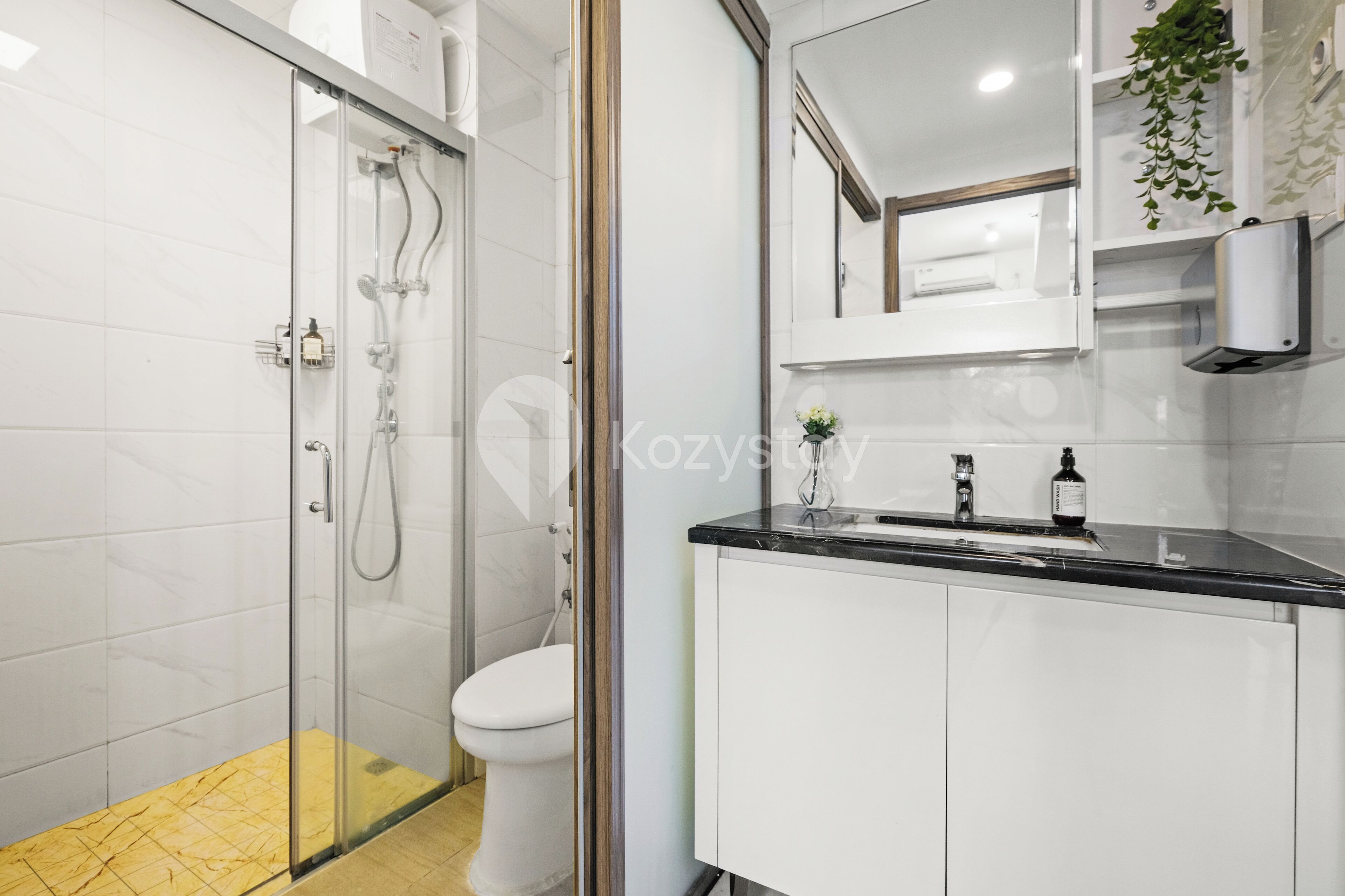 A modern bathroom with a glass shower enclosure, a white toilet, and a black countertop with a sink.