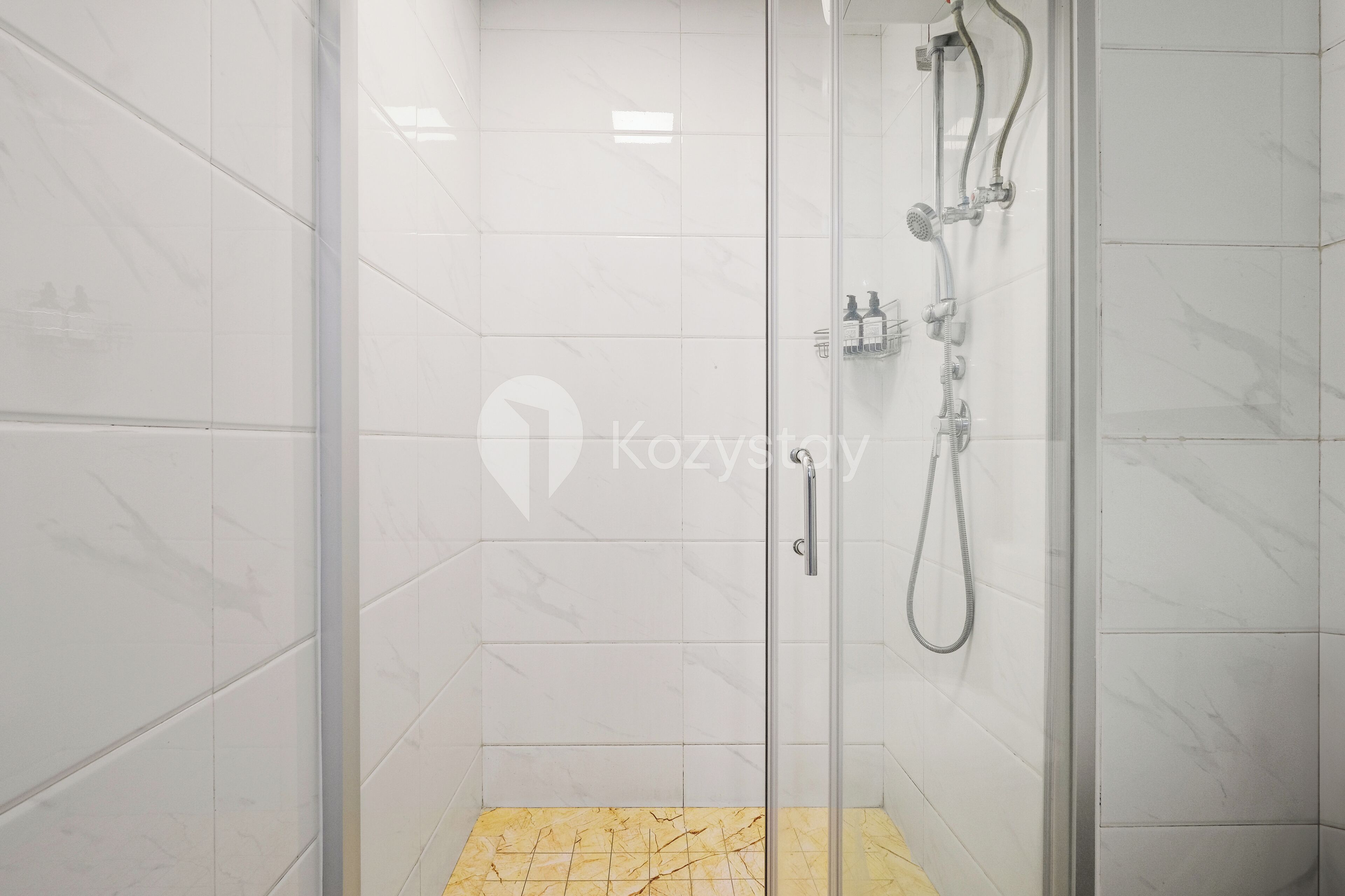 A glass-enclosed shower area with white marble tiles and a yellow-tiled floor.