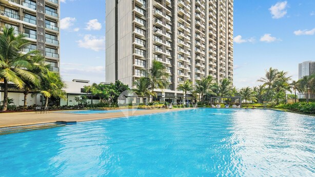 A swimming pool with a view of tall residential buildings and palm trees. - Belia by Kozystay - BSD (Pagedangan)