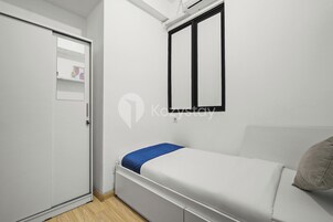A small, modern room with a bed, a wardrobe, and a window.