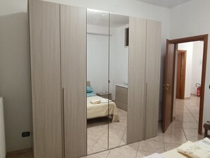 Une chambre avec une grande armoire, un lit avec un oreiller bleu et une petite table de chevet.