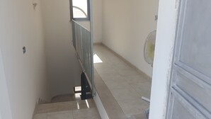 A narrow stairwell with a metal railing, a small window, and a fan on the landing. - Home  Peppe (Manduria)