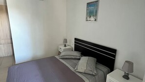 Ein Schlafzimmer mit einem Bett, zwei Nachttischen, einem Wandgerät zur Klimatisierung und einem Bild.