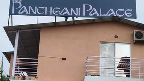 Une enseigne indiquant l’entrée du Panchgani Palace, avec un balcon et une porte.
