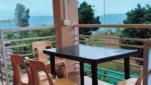 Un espace extérieur abrité, avec une table et des chaises, offrant une vue sur un paysage verdoyant et une étendue d’eau.