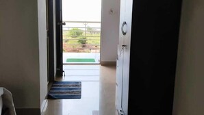 Une pièce dotée d’une grande armoire, d’une porte donnant sur un balcon et d’un petit tapis sur le sol.
