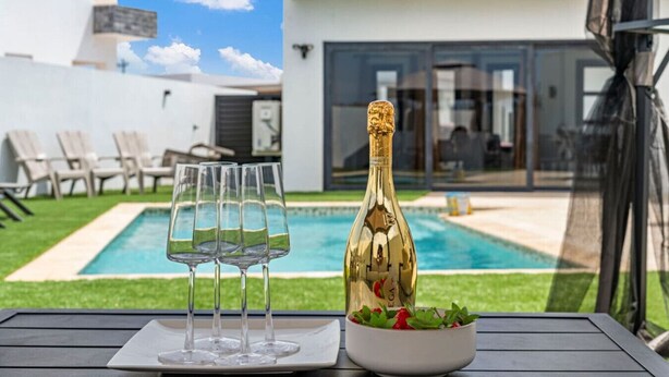 A poolside table with a bottle of champagne, glasses, and a bowl of strawberries. - 3BR Villa in Aruba · Private Pool · Prime Location (Noord)