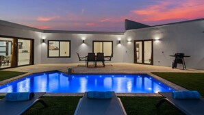 A modern outdoor pool area with a clear view of the sky, a dining table, and lounge chairs. - 3BR Villa in Aruba · Private Pool · Prime Location (Noord)