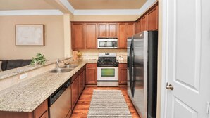 A compact kitchen with wooden cabinets, stainless steel appliances, and a granite countertop. - Luxurious Three-Story Townhome in Houston (Houston)