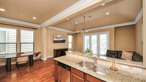 A spacious kitchen with granite countertops, a dishwasher, and a large island with a sink. - Luxurious Three-Story Townhome in Houston (Houston)