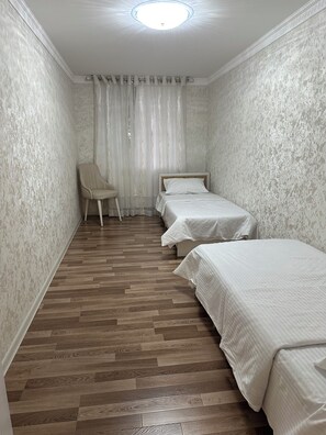 A narrow room with two beds, a chair, and a patterned wall. - Boulevard Guest House by SamApart (Samarqand)