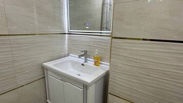 Un baño moderno con un lavabo blanco, un espejo y una cortina de ducha.