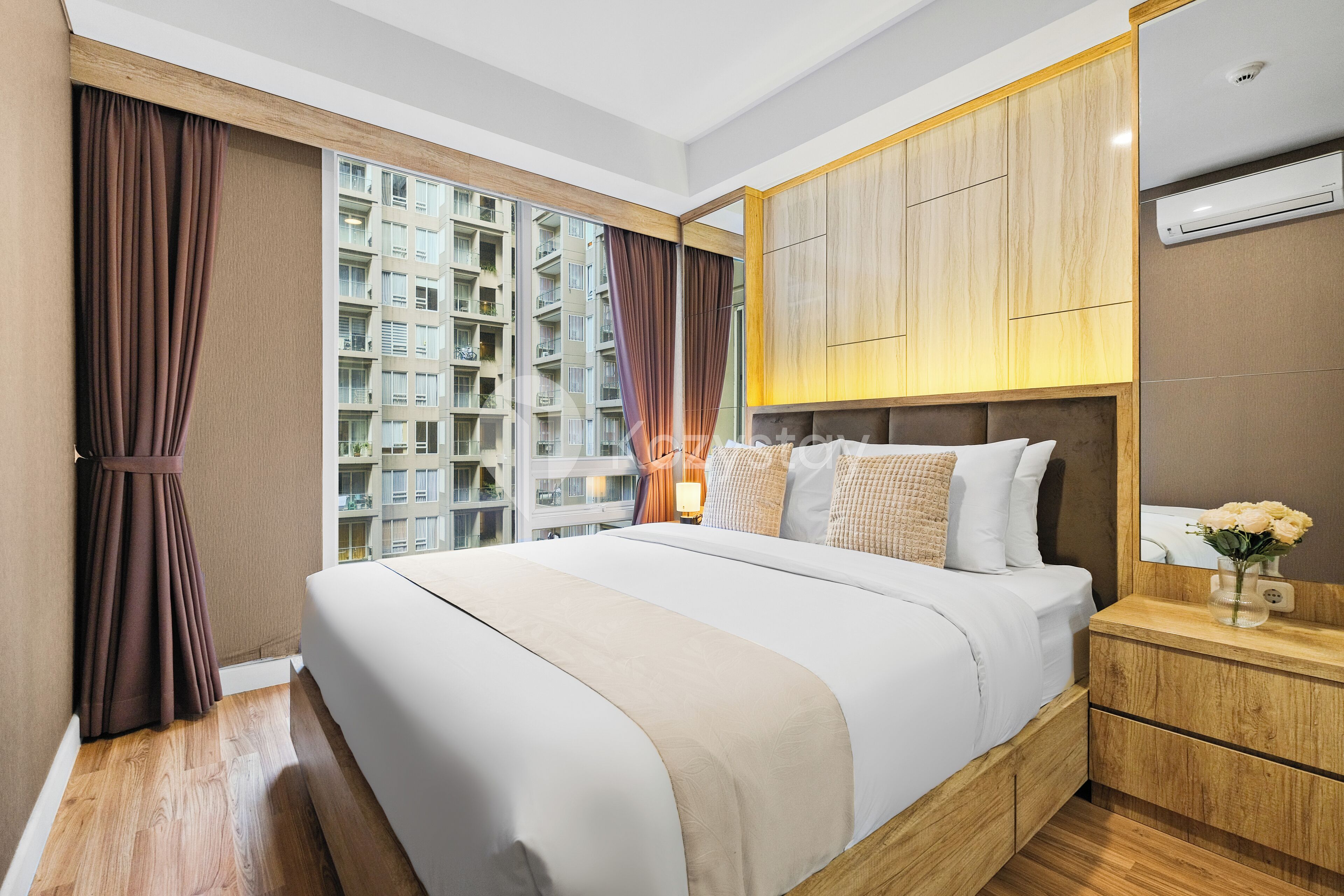 Una habitación de hotel moderna con una cama grande, cabecera de madera y vistas a edificios altos.