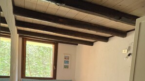 Een slaapkamer met twee bedden, een raam, een nachtkastje en een klein tafeltje.