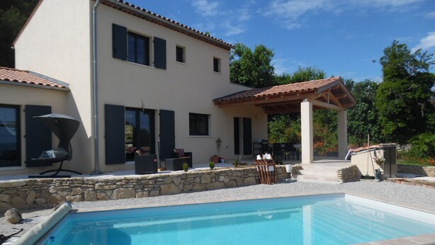 Una casa de dues plantes amb piscina, mobiliari exterior i una pèrgola.