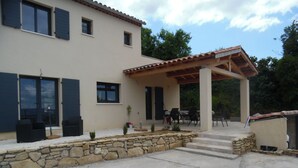 Una casa de dues plantes amb terrassa coberta, piscina i zona d'estar a l'aire lliure.