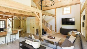 Un vaste espace de vie doté d’un plafond en bois, d’un escalier, d’une télévision et d’un canapé.