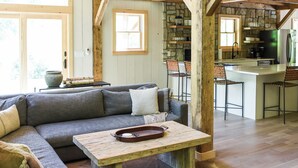 Un vaste espace de vie comprenant un grand canapé, une table basse en bois et un mur en pierre.