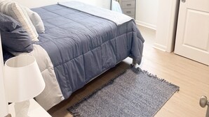 A bedroom with a bed, a bedside table with a lamp, a mirror, a dresser, and a door. - Shore Thing Wildwood (Wildwood)