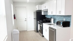 A modern kitchen with white cabinets, a black refrigerator, a stove, and a microwave. - Shore Thing Wildwood (Wildwood)