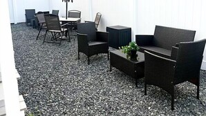 An outdoor patio area with a white fence, black wicker furniture, and a table with chairs. - Shore Thing Wildwood (Wildwood)