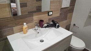 A bathroom with a white sink, a mirror, a hairdryer, and a toilet. - Appia Antica Room (Marino)