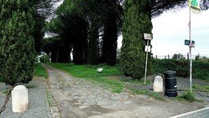 A cobblestone path leading through a park with tall trees and a signpost. - Appia Antica Room (Marino)