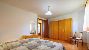 Une chambre avec un grand lit, une armoire en bois et une chaise.